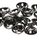 Close-up of shiny black metal Brassonics Discs with multiple holes, designed for use in fishing tackle and lure customization.