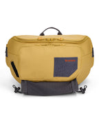 Simms Tributary Hip Pack in mustard yellow with multiple zippered compartments, a front felt patch with embroidered logo, and adjustable straps for secure, comfortable carry.