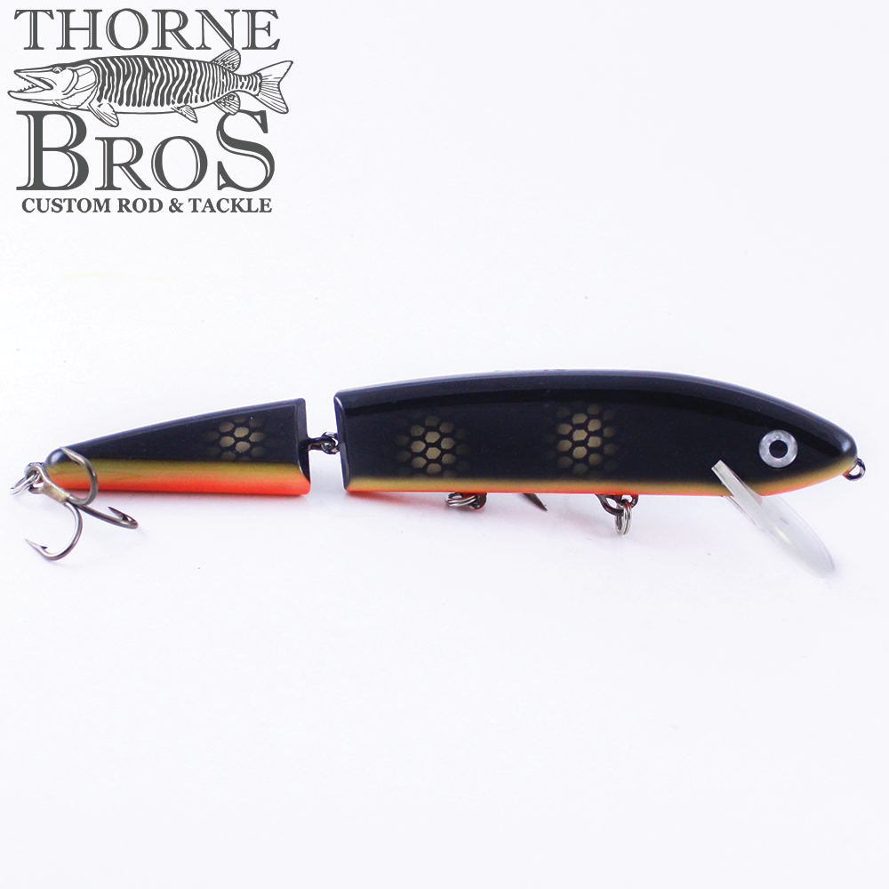 Inhaler - 8" Jointed fishing lure in black and orange with segmented body and lifelike eye, designed for musky fishing by Thorne Bros Custom Rod & Tackle.