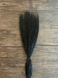Black synthetic fishing lure material with subtle sparkle strands laid out on a wooden surface, designed for use with Squimpish Sparkle Blend fishing tackle.
