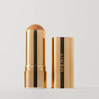 Quince | |  A stick bronzer product by MERIT, with the cap off, showing the bronzing cream inside and MERIT on the cap. Shade Quince