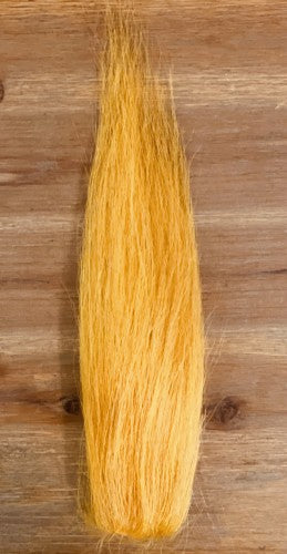Close-up image of bright yellow synthetic fibers arranged in a tapered bundle, used for the Squimpish Hair fishing lure in musky tackle.